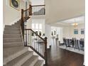 Grand foyer view with staircase and railing, hardwood floors, high ceilings, and open access to the dining and living areas at 3715 Kendall Wood Dr, Carmel, IN 46032