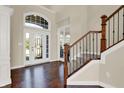 Bright foyer with hardwood floors, staircase with decorative iron railing, and a large window above the front door at 3715 Kendall Wood Dr, Carmel, IN 46032
