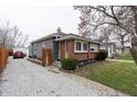 Charming home showcasing brick and gray siding, a stone driveway, complemented by a blossoming tree at 4711 East 21St St, Indianapolis, IN 46218