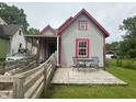 This cute house features gray siding, red trim, a wooden ramp, and a patio with outdoor seating at 554 N Tacoma Ave, Indianapolis, IN 46201
