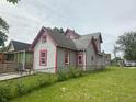 View of a two-story home with gray siding, red trim, and a spacious lawn at 554 N Tacoma Ave, Indianapolis, IN 46201