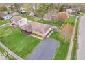 Aerial view of a home with a large driveway, green lawn, mature trees, and fenced backyard at 66 Coronado Rd, Indianapolis, IN 46234