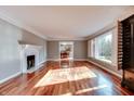 Bright living room with hardwood floors, a fireplace, large window, and decorative molding at 7525 N Meridian St, Indianapolis, IN 46260