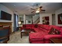 Spacious living room featuring plush red sofa, ceiling fan, and staircase at 8358 Balmoral Dr, Avon, IN 46123