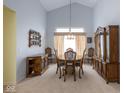 Formal dining area with high ceilings, elegant chandelier, and wooden furniture set against light blue walls at 8737 Champions Dr, Indianapolis, IN 46256