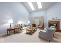 Bright living room with vaulted ceiling, skylights, a fireplace, and comfortable seating arrangements at 8737 Champions Dr, Indianapolis, IN 46256