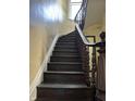 Elegant staircase featuring dark wood steps and handrail, complemented by a white trim and textured wall at 902 N Broadway St, Indianapolis, IN 46202