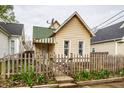 Quaint front exterior featuring a peaked roof, picket fence and garden beds with tulips at 902 Villa Ave, Indianapolis, IN 46203
