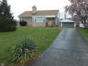 Lovely home with a stone exterior, lush front yard, long driveway, and a detached garage at 1106 N Hartman Dr, Indianapolis, IN 46219