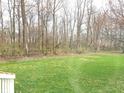 An open and green backyard lawn with trees and a partial view of the property's back deck at 12441 Bent Oak Ln, Indianapolis, IN 46236