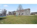 Fenced backyard featuring a grass yard, play set, trampoline, and durable siding at 1436 Amberwoods Ct, Indianapolis, IN 46239