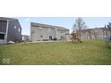 A spacious backyard with a grass yard, a play set, a basketball hoop, and a concrete patio at 1436 Amberwoods Ct, Indianapolis, IN 46239