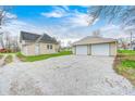 View of the home and a detached two-car garage with a gravel driveway at 156 S Cross St, Clayton, IN 46118
