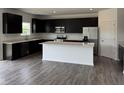 Modern kitchen with black cabinets, stainless steel appliances, an island, and hardwood flooring at 211 Ames Dr, Whiteland, IN 46184