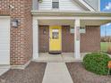 Close up of the red brick front porch and vibrant yellow front door of this lovely home at 2207 Mcgregor Ct, Avon, IN 46123