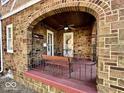 Cozy front porch with brick archway, seating area, and ceiling fan at 303 S Walnut St, Edinburgh, IN 46124