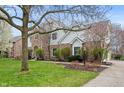 Beautiful two-story brick and white home featuring mature trees and landscaped front yard at 325 W Greyhound Pass, Carmel, IN 46032