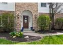 Elegant front entry with brick archway, decorative door, and neatly arranged flower pots at 325 W Greyhound Pass, Carmel, IN 46032