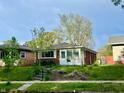 Quaint brick home features a bright sunroom, manicured lawn, and mature trees for shade at 4151 Bowman Ave, Indianapolis, IN 46227