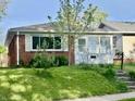 Attractive brick home featuring a sunroom and neat front lawn with young tree at 4151 Bowman Ave, Indianapolis, IN 46227