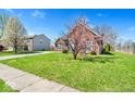 Expansive front yard with lush green grass complements this charming brick home at 7854 Crooked Meadows Dr, Indianapolis, IN 46268