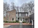Striking two-story home featuring a blend of stone and contemporary siding, accentuated by mature trees and professional landscaping at 8224 Claridge Rd, Indianapolis, IN 46260