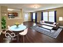 Open living room with hardwood floors, a modern rug, and a gray sofa under natural light at 11876 Wapiti Way, Noblesville, IN 46060