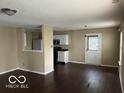 Open-concept living room with view of kitchen, hardwood floors, and bright entry door at 11876 Wapiti Way, Noblesville, IN 46060