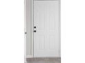 A white six-panel front door with black hardware stands out against a light gray wall at 1512 Tipton Ln, Columbus, IN 47201