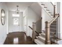 Inviting foyer featuring hardwood floors, a staircase with iron railings, and elegant light fixtures at 15679 Woodford Dr, Westfield, IN 46074