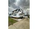 View of the home with a covered porch and detached garage, offering ample parking space at 1627 E 8Th St, Anderson, IN 46012