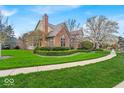 Attractive brick home with a neatly landscaped yard, including green grass, mature trees, and a paved sidewalk at 328 Millridge Dr, Indianapolis, IN 46290