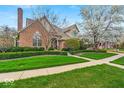 Beautiful brick home showcasing lush green lawn, trimmed hedges and a sidewalk, providing curb appeal at 328 Millridge Dr, Indianapolis, IN 46290