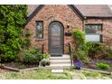 Home's entrance, showing brick, stone path, and arched front door with small windows on each side at 5683 Guilford Ave, Indianapolis, IN 46220
