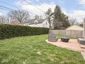 Well-maintained backyard features a lush lawn, trimmed hedges, and patio with outdoor seating at 645 N Ritter Ave, Indianapolis, IN 46219