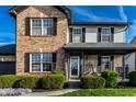 Close up of a two-story brick home with vinyl siding, manicured bushes, and a charming covered front entry at 1228 Knapps Ct, Greenwood, IN 46142