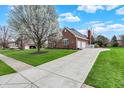 Charming red-brick home showcasing an attached garage, a paved driveway, and verdant landscaping at 13225 Snow Owl Dr, Carmel, IN 46033