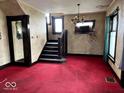 Classic living room with red carpet, vintage chandelier, and original architectural details and moldings at 1325 S Hackley St, Muncie, IN 47302