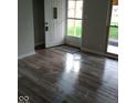 Inviting entryway featuring glossy light-colored wood flooring, gray walls, and a storm door at 1502 Saint John S Ct, Beech Grove, IN 46107
