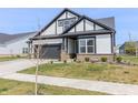 Attractive home with gray siding, black trim, a well-manicured lawn, and a freshly planted tree at 15755 Scher Dr, Westfield, IN 46074
