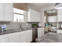 Bright kitchen with white cabinets, gray tile backsplash, granite countertops, and stainless steel appliances at 3246 Fawn Cir, Brownsburg, IN 46112