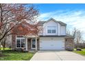 Charming two-story home boasts brick and white siding, attached two-car garage and well-manicured lawn at 4345 Elkhorn Dr, Westfield, IN 46062