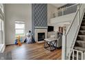 Cozy living room with a fireplace, large window, and staircase leading to a second-floor balcony at 4345 Elkhorn Dr, Westfield, IN 46062