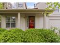 Up-close view of home's front entry featuring lush shrubs and a bright red door at 6404 Bayside Ct, Indianapolis, IN 46250