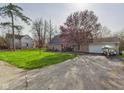 Inviting brick home features a long driveway, green lawn, and attached two-car garage at 6413 N Wheeling Ave, Muncie, IN 47304