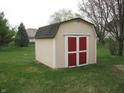 Backyard view of storage shed with red doors and beige siding at 10762 Galant Fox Ct, Indianapolis, IN 46234