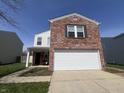 Charming two-story home featuring a brick front, attached garage, and a well-maintained lawn at 1404 Alonzo Pl, Indianapolis, IN 46217