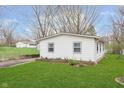 Rear exterior showcasing a tidy lawn and the home's clean white siding, complemented by neat landscaping and a detached garage at 1946 N Riley Ave, Indianapolis, IN 46218