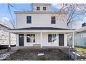 Charming two-story home featuring a covered front porch with white accents and black doors at 241 N Tacoma Ave, Indianapolis, IN 46201