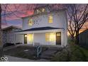 Charming two-story home featuring a covered front porch with white accents and black doors at dusk at 241 N Tacoma Ave, Indianapolis, IN 46201